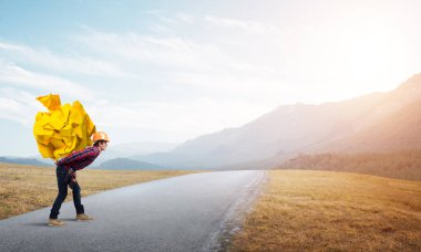 Sırtında kağıt top taşıyan inşaatçı.