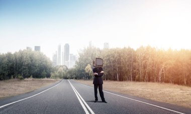 İş başına silah tutmak yerine eski Tv ile takım elbiseli adamı ayakta arka plan üzerinde güzel manzara ile yolda geçti.