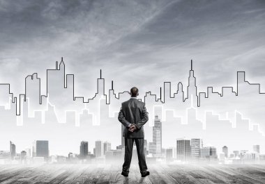 İşadamı arkasını dönüp modern iş merkezinin siluetine bakıyor.