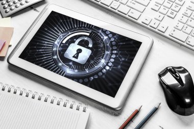 Ofis eşyalarıyla iş yeri ve ekranda asma kilit simgesi olan tablet
