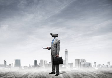 Şehir planına kafa atmak yerine kamerayla zum yapan yüzsüz bir iş adamı.