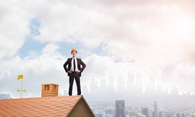 Takım elbiseli genç işadamı ve çatıda kask var. Karışık ortam