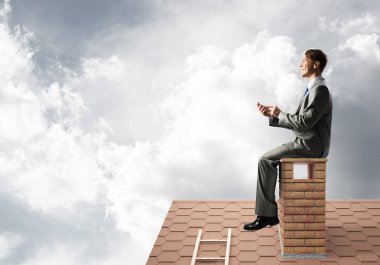 Elinde cep telefonu ile evin baca oturan genç işadamı