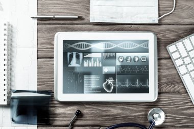Beyaz tablet bilgisayar ve doktor aletleri ahşap masada.