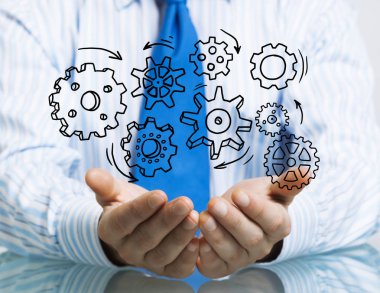 Masada oturan ve dişli mekanizması avuç içi gösterilen işadamı yakın çekim