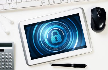 Ofis eşyalarıyla iş yeri ve ekranda asma kilit simgesi olan tablet