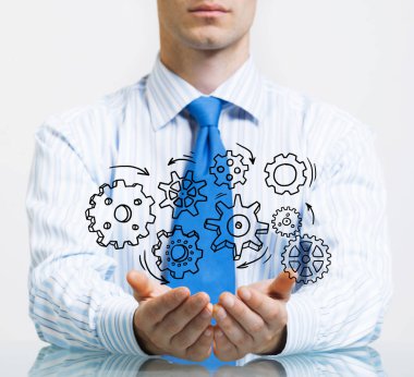 Masada oturan ve dişli mekanizması avuç içi gösterilen işadamı yakın çekim