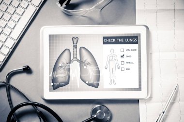 Gri yüzeyde beyaz tablet ve doktor araçları