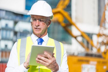 Kıdemli mühendis erkek takım elbise ve tablet PC'de çalışma kask