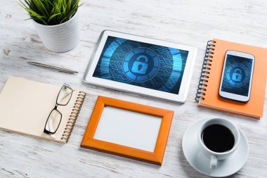 Ofis eşyalarıyla iş yeri ve ekranda asma kilit simgeleri olan tablet