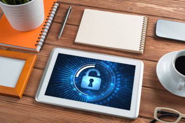Ofis eşyalarıyla iş yeri ve ekranda asma kilit simgeleri olan tablet