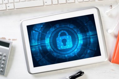 Ofis eşyalarıyla iş yeri ve ekranda asma kilit simgesi olan tablet