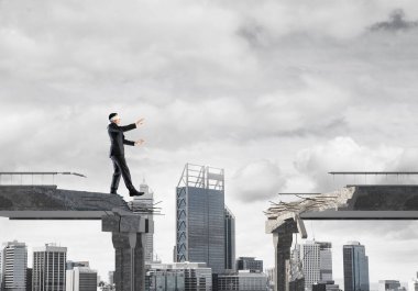 Gizli tehditlerin ve risklerin sembolü olarak beton köprüde gözü kapalı yürüyen bir iş adamı. Arka planda şehir manzarası. 3B görüntüleme.