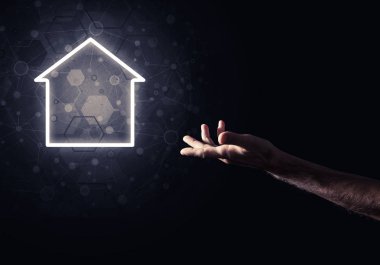 İnsanın eli parlayan ev simgesi ya da sembolüyle dokunuyor