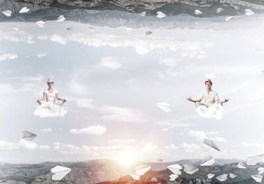 Genç çift gözleri koruma kapalı ve seyir bulutlar arasında kağıt uçaklar uçuyor ve doğa dünyalar arasında üzerinde meditasyon sırasında konsantre.