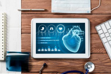 Beyaz tablet bilgisayar ve doktor aletleri ahşap masada.