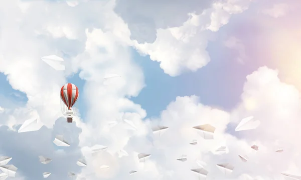 stock image Colorful aerostat flying among paper planes and over the blue cloudy sky. 3D rendering.