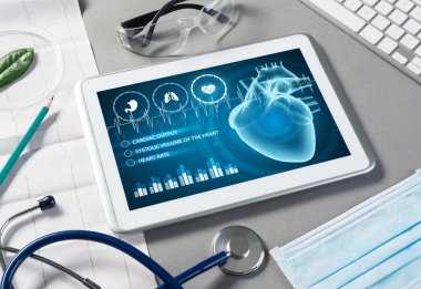 Gri yüzeyde beyaz tablet ve doktor araçları