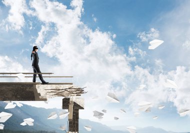 Gizli tehditlerin ve risklerin sembolü olarak beton köprüde gözü kapalı yürüyen bir iş adamı. Arka planda gökyüzü ve doğa manzarası. 3B görüntüleme.