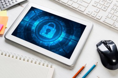 Ofis eşyalarıyla iş yeri ve ekranda asma kilit simgesi olan tablet