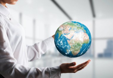 Yan görünümü closeup gömlekli dünya küre arka plan üzerinde office manzaralı elinde tutan bir iş kadını. Bu görüntü unsurları Nasa tarafından döşenmiştir.