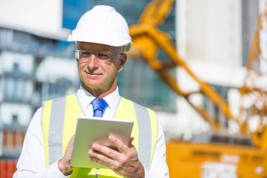 Kıdemli mühendis erkek takım elbise ve tablet PC'de çalışma kask