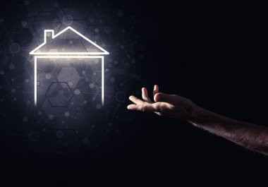 İnsanın eli parlayan ev simgesi ya da sembolüyle dokunuyor