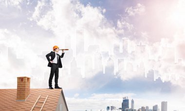 Takım elbiseli genç işadamı ve çatıda kask var. Karışık ortam