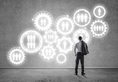 İş adamının çizilmiş dişli mekanizmasıyla duvara baktığı arka plan