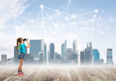 Şirin kız ahşap bir zeminde duruyor ve dürbünle izliyor.