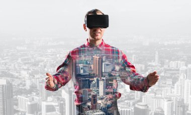 Sanal gerçeklik kulaklığı olan genç bir adam ya da şehrin arka planında 3 boyutlu gözlüklü.