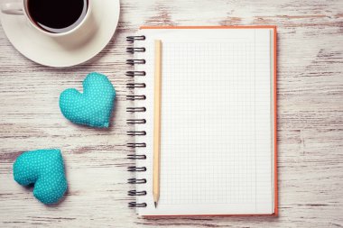 Kahve fincanı not defteri kalem ve ahşap yüzeyde iki kalp