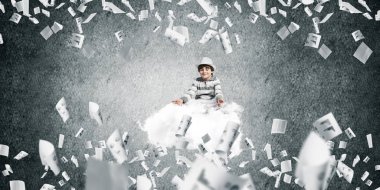 Genç küçük çocuk gözleri koruma kapalı ve seyir üzerinde uçan bulut ile gri karanlık duvar kağıtları arka plan üzerinde uçan arasında meditasyon sırasında konsantre.