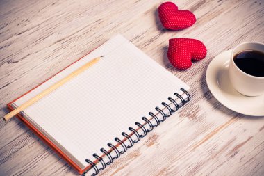 Kahve fincanı not defteri kalem ve ahşap yüzeyde iki kırmızı kalp