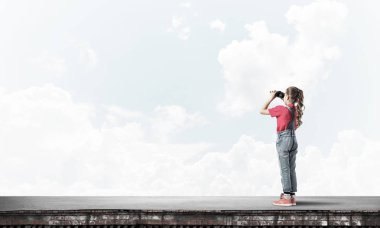 Dürbünle bakan, okul çağındaki sevimli kız çatıyı inşa ediyor.