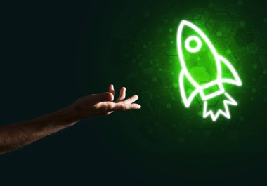 Koyu arkaplanda parlayan roket simgesi ve insan eli