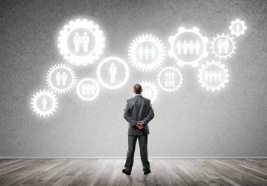 İş adamının çizilmiş dişli mekanizmasıyla duvara baktığı arka plan