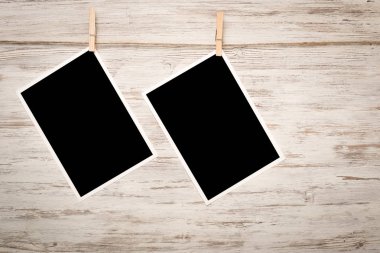 Boş fotoğraf çerçevesi ahşap bir zeminde ipte asılı.