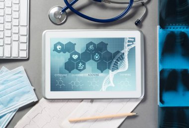 Gri yüzeyde beyaz tablet ve doktor araçları