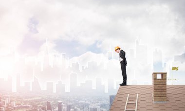 Takım elbiseli genç işadamı ve çatıda kask var. Karışık ortam