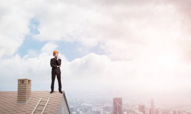 Takım elbiseli genç işadamı ve çatıda kask var. Karışık ortam