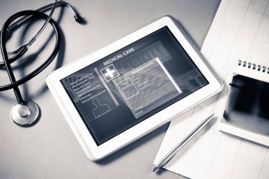 Gri yüzeyde beyaz tablet ve doktor araçları