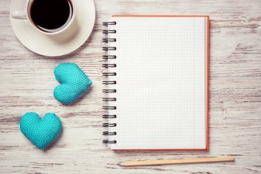 Kahve fincanı not defteri kalem ve ahşap yüzeyde iki kalp