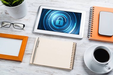 Ofis eşyalarıyla iş yeri ve ekranda asma kilit simgeleri olan tablet