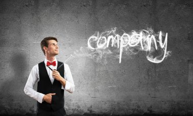 Akıllı-rahat, kendinden emin ve genç işadamı yatay atış yasaktır boru gri karanlık duvar ve duman arka plan üzerinde yapılan şirket kelime karşı dururken giymek.