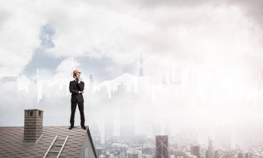 Takım elbiseli genç işadamı ve çatıda kask var. Karışık ortam