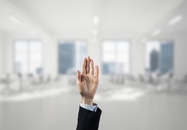 İş kadınının eli ekranda kapalı ve arka planda avuç içi ve ofis