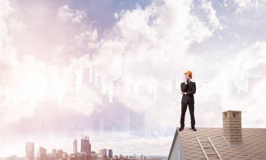 Takım elbiseli genç işadamı ve çatıda kask var. Karışık ortam