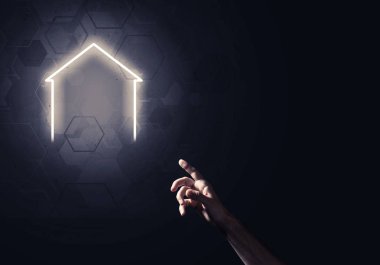 İnsanın eli parlayan ev simgesi ya da sembolüyle dokunuyor