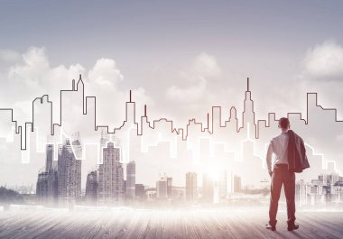 İşadamı arkasını dönüp modern iş merkezinin siluetine bakıyor.